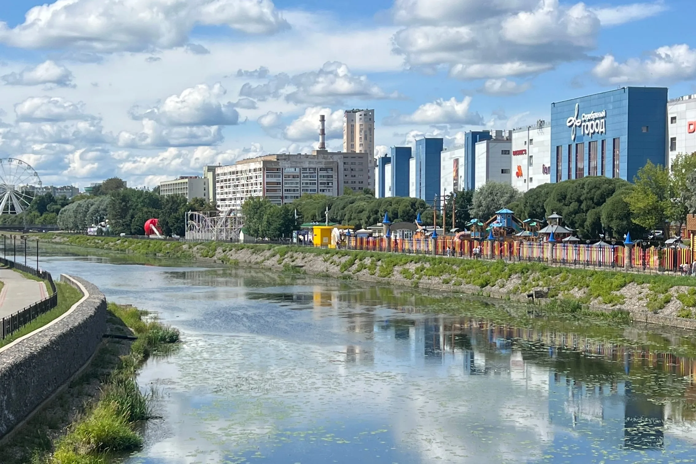 Река Уводь в Иванове, за ней набережная с детской площадкой и городские многоэтажки