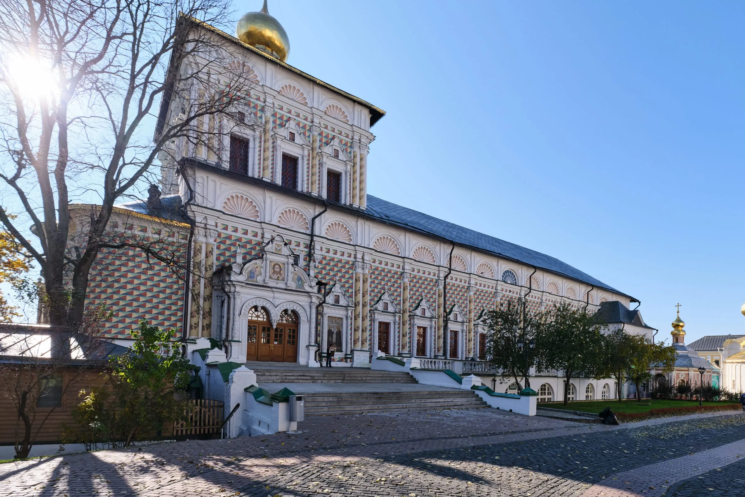 Расписанный в шахматную клетку фасад Трапезной церкви Троице-Сергиевой лавры с раковинами в карнизе и золотым куполом